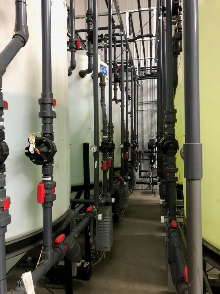 An aisle of vertical process piping and valves.