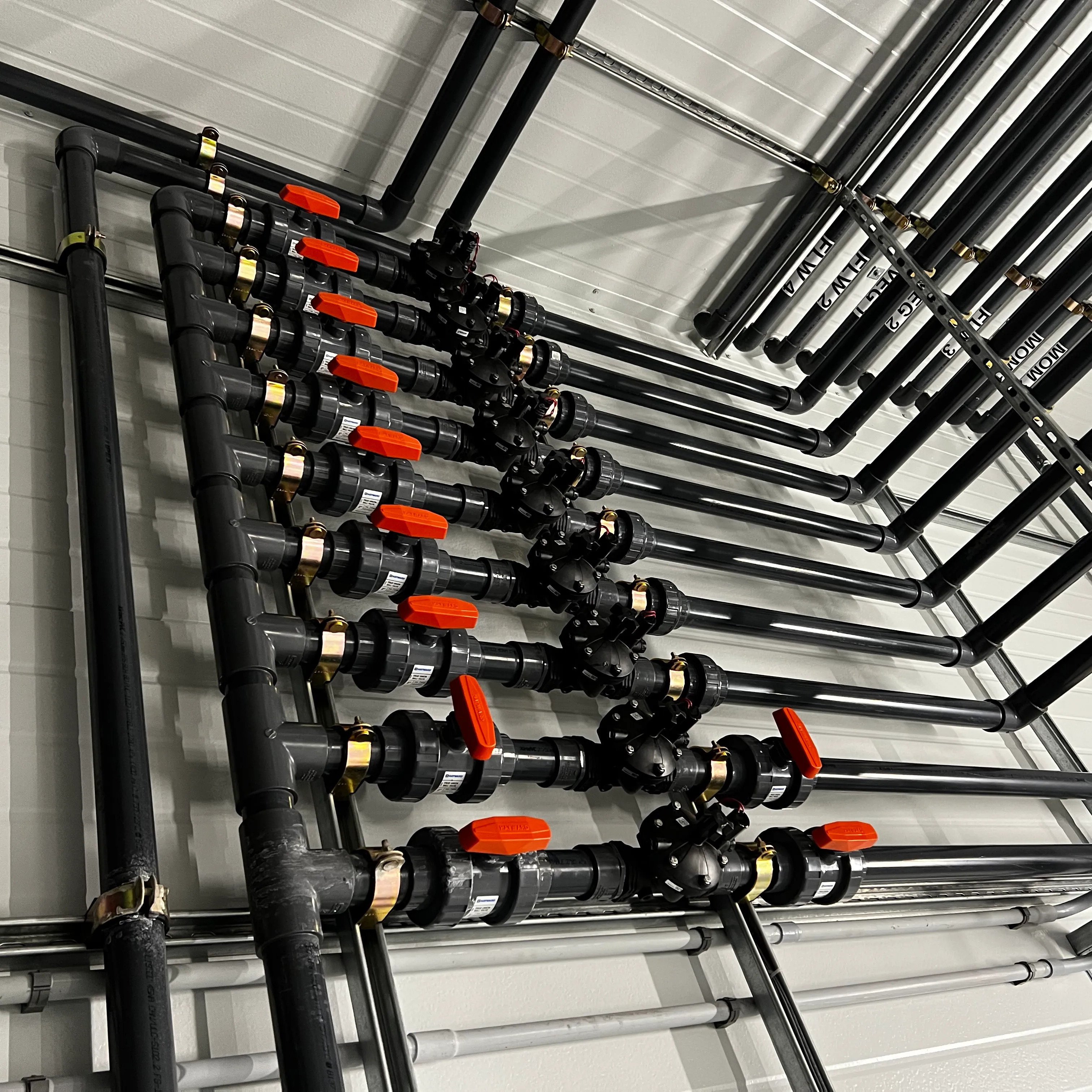 Manifold with orange-handled valves and gray PVC risers.